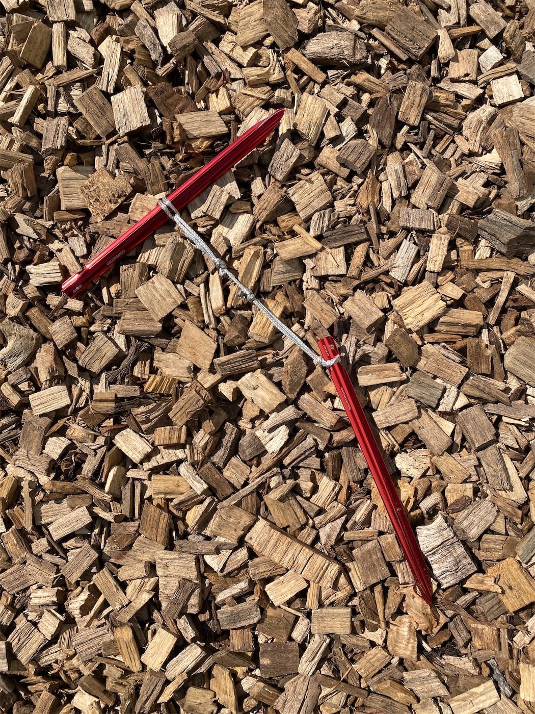 Then loop the loop through itself (cow hitch?) and around each peg. One end around the middle of something, a mallet, another peg, to form the handle. The other end slipped around the notches, to give an anchor point to pull against.